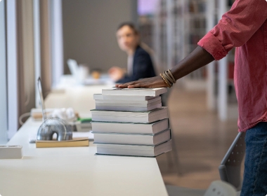 hand-hold-stack-of-books-on-library-table-prepared-2025-03-07-09-29-26-utc